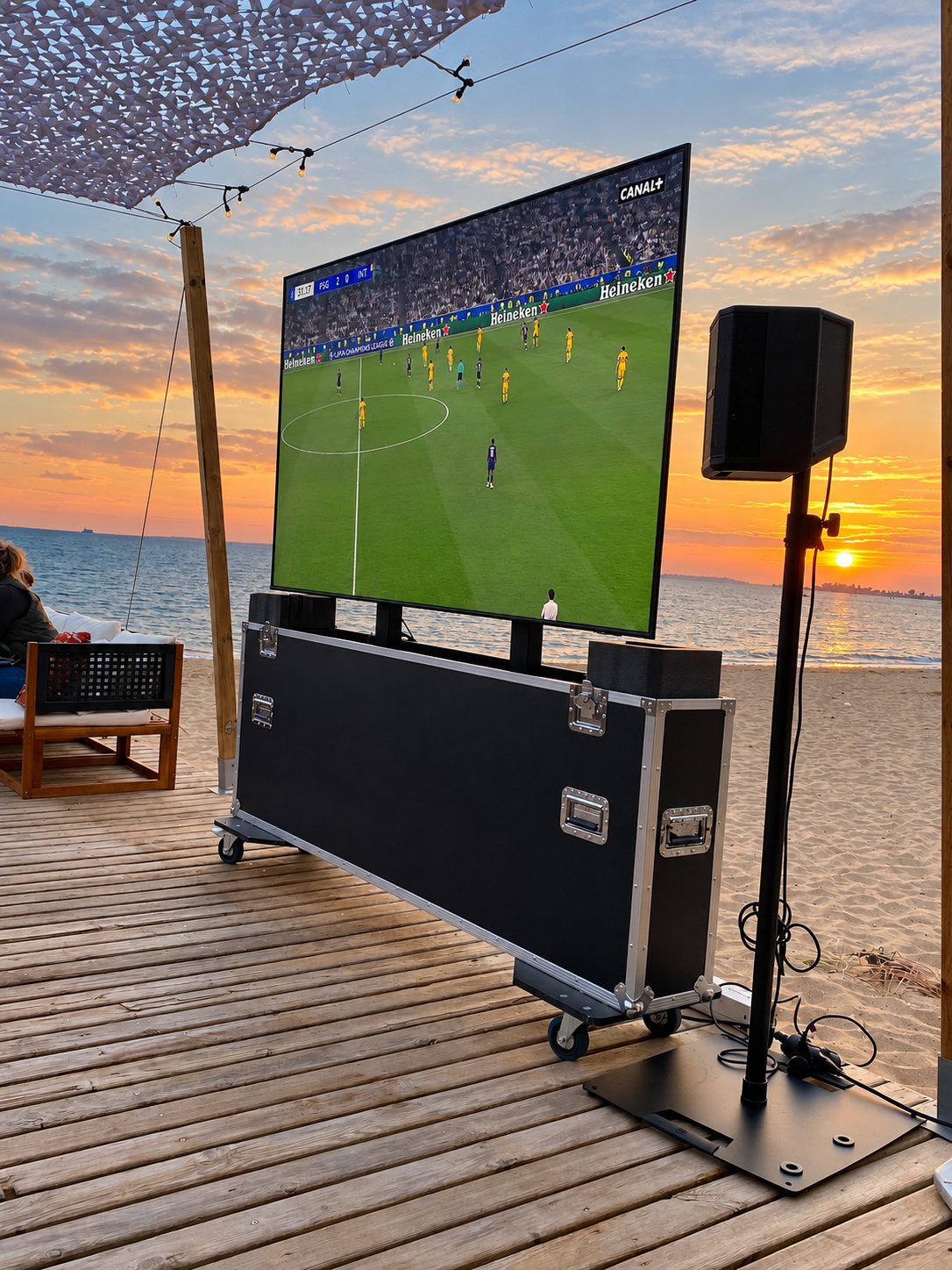 Écran et enceinte pour la diffusion d’un match sur une terrasse face à la mer