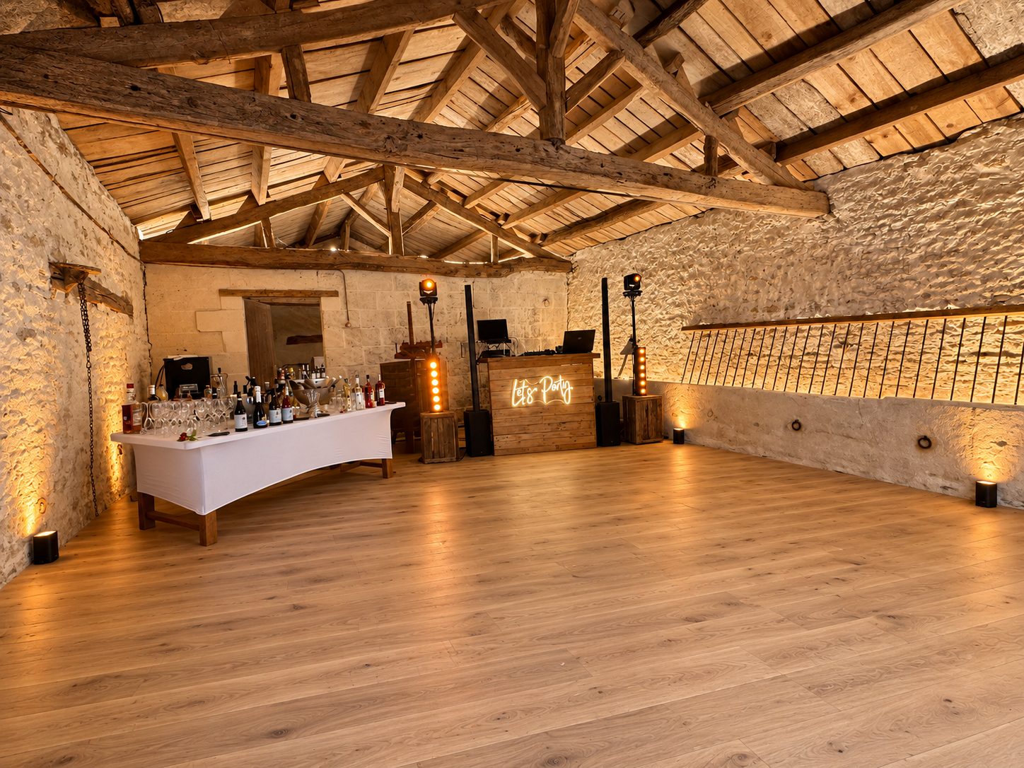 Installation DJ et piste de danse sous une charpente en bois, avec éclairage ambré