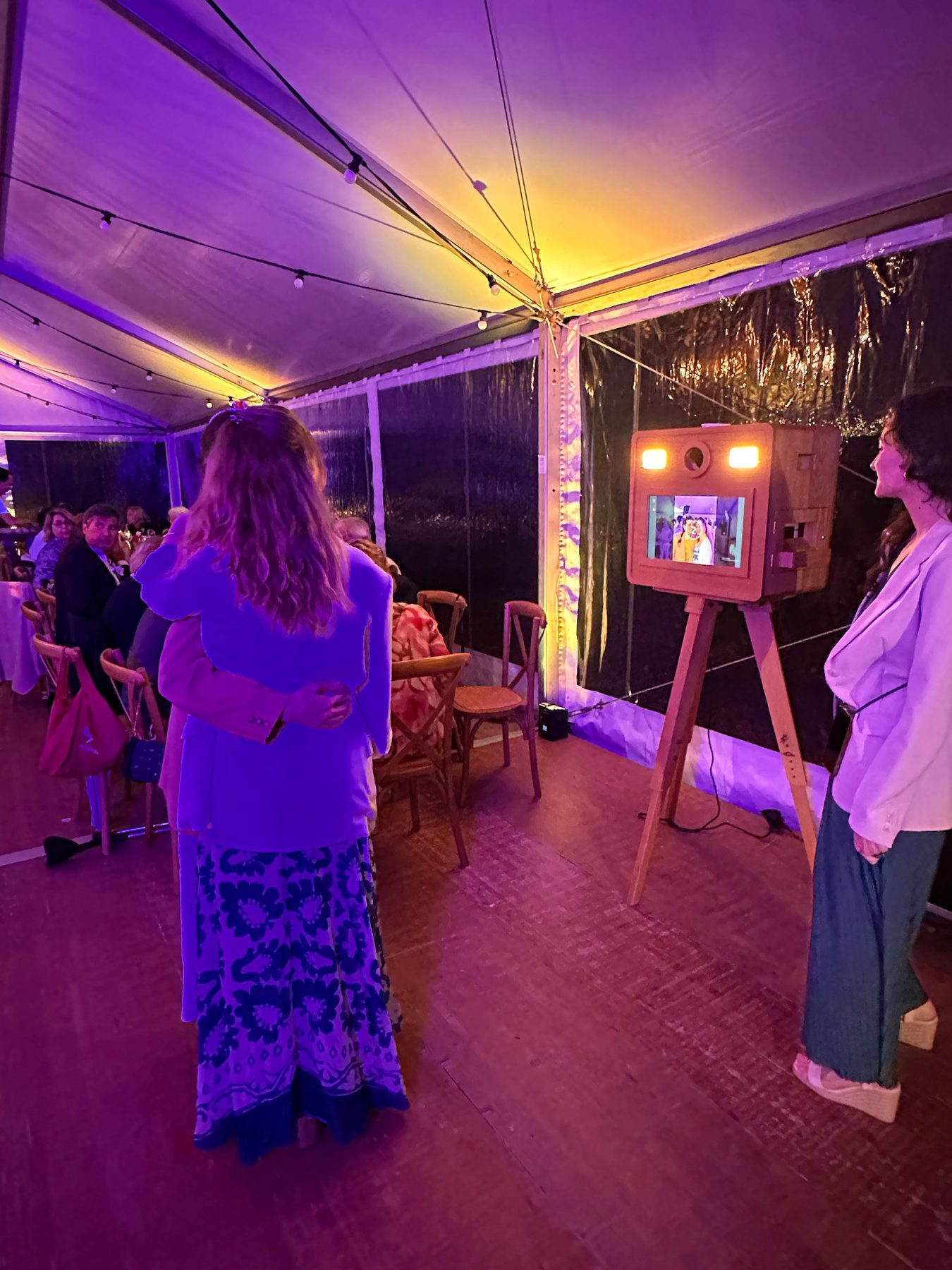 Invités autour du photobooth lors d’une soirée sous une tente